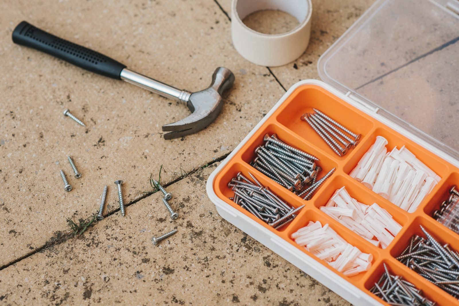 A compartment tray of screws and fixings beside a hammer