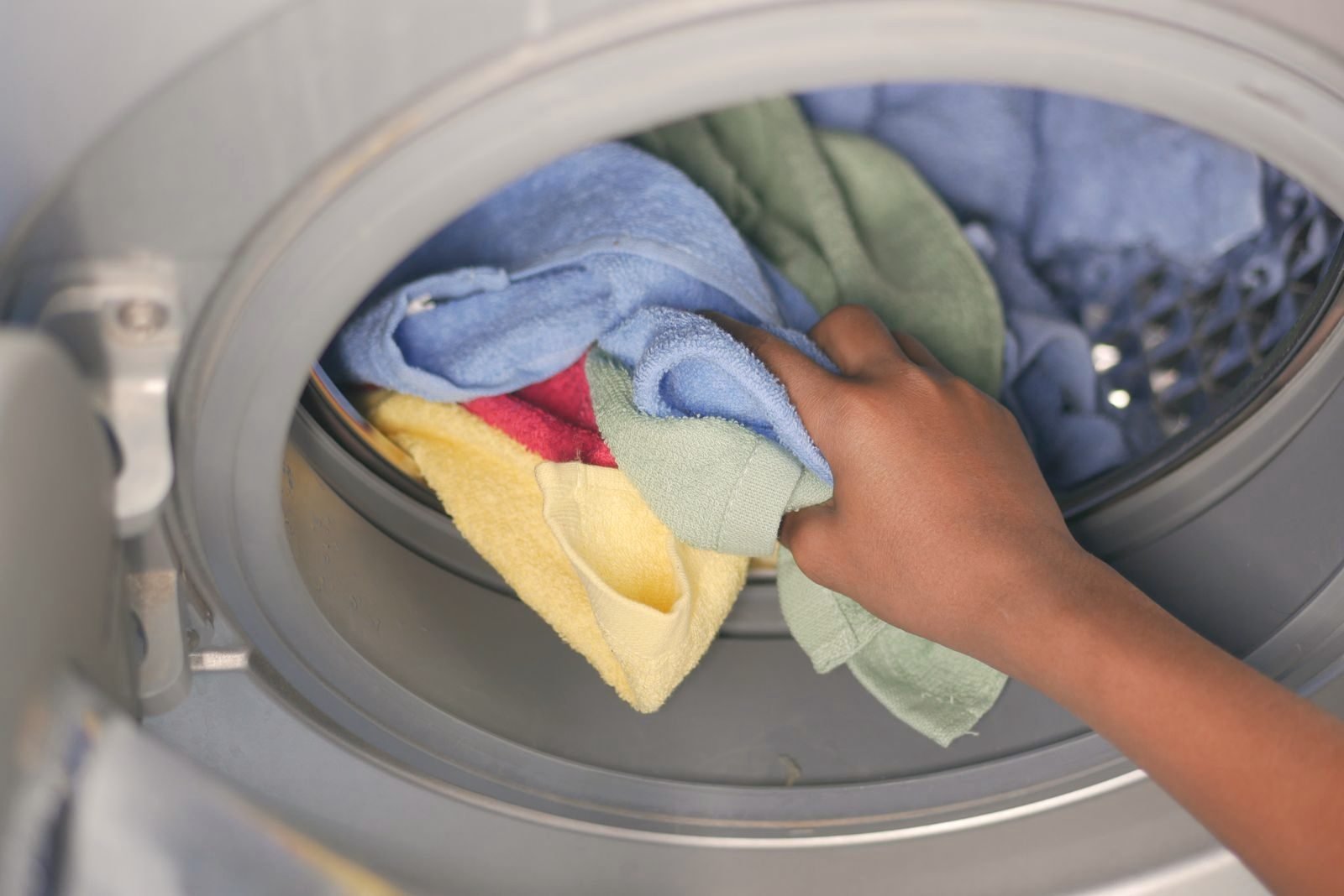 Colourful towels going into a front-load washer drum