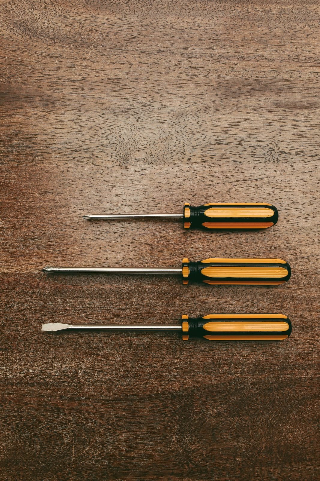 Three screwdrivers laid in a row on wood